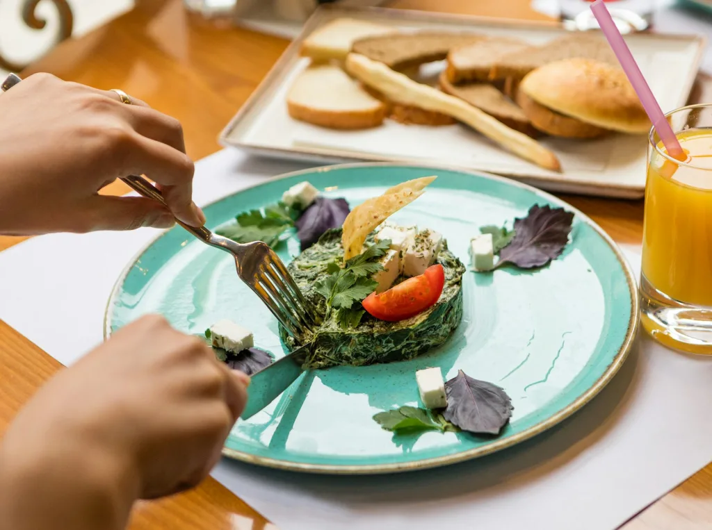 person holding fork and knife slicing vegetable on white ceramic plate