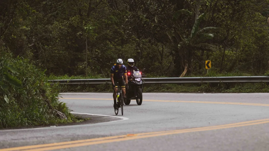 a couple of people riding bikes down a curvy road